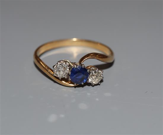 A yellow metal, sapphire and diamond three stone crossover ring, size O, gross weight 2.3 grams.